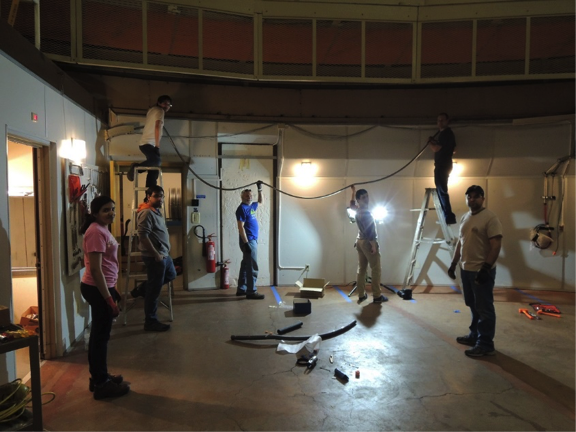  Utilization of the du Pont telescope required retrofitting to accommodate the needed infrastructure. Here, the fiber train, which runs between the telescope and the instrument located one floor below, is installed along the perimeter of the observing floor during commissioning. <em>Photo courtesy of S. Majewski</em> 