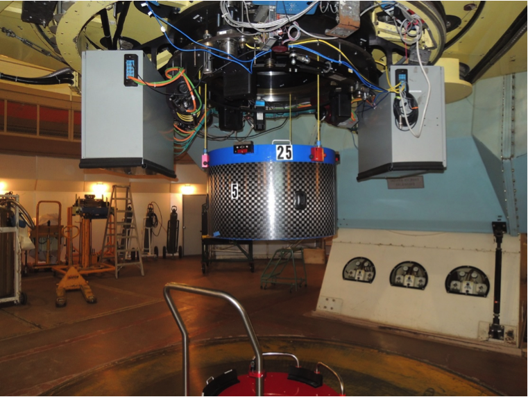  A plugged cartridge is hoisted into place at the Cassegrain focus of the du Pont Telescope using an intricate mounting system. <em>Photo courtesy of J. Wilson.</em> 